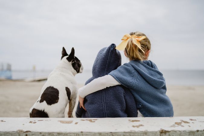 Kids hugging dog on beach