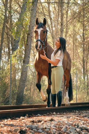 Smiling equestrian with horse in forest