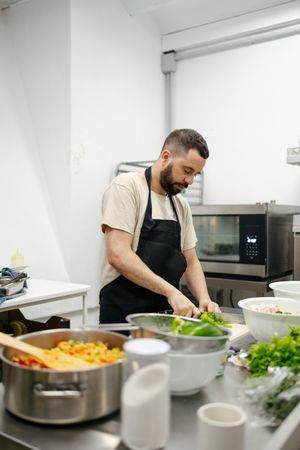 Young chef cutting peppers