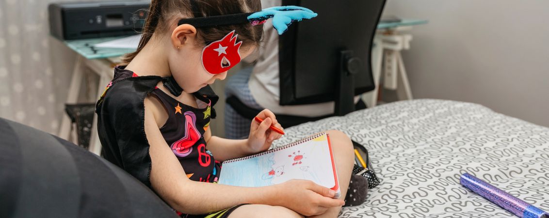 Girl drawing in disguise while her mother teleworking