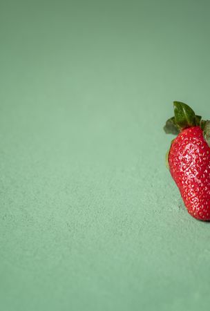 Partial of one strawberry on green background