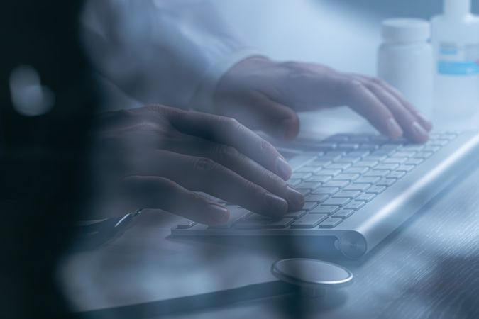 Doctor working at computer keyboard through X-ray film