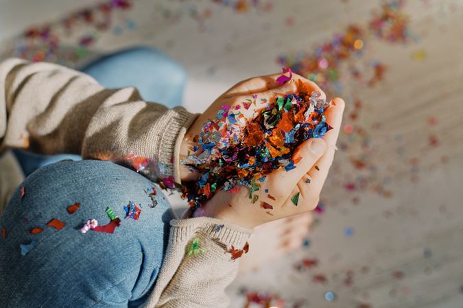 Boy collecting bright confetti from floor