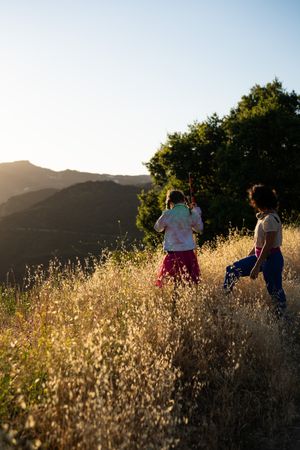 Daughter and mother exploring through the grass on a mountain at sunset