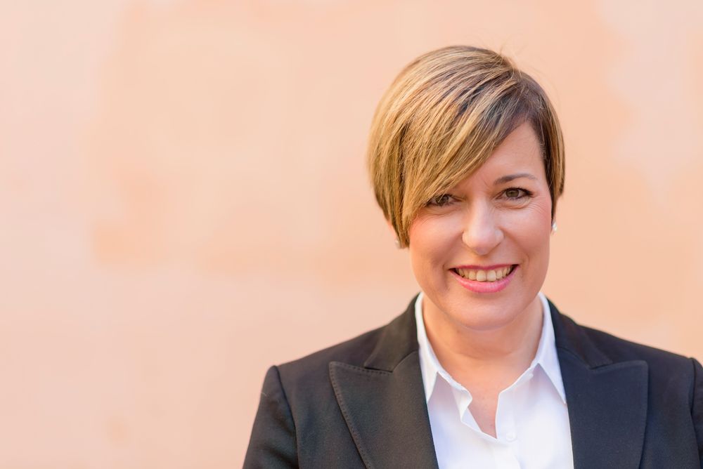 Portrait of woman in blazer in front of peach background