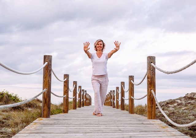 Cheerful woman exercising on timber path