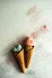 Two ceramic hearts in waffle cones on grey background with glitter