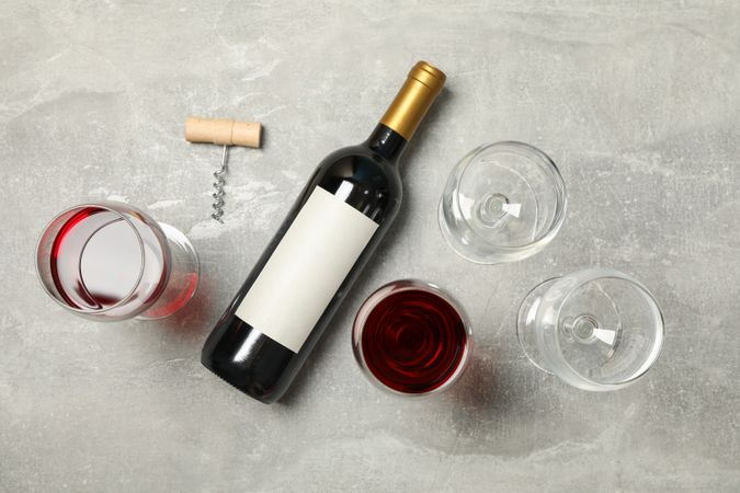 Flat lay composition with bottle and glasses of wine, corkscrew on grey background, copy space