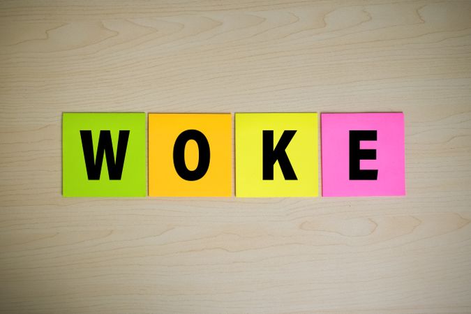 woke word symbol on colorful sticky notes on wooden background