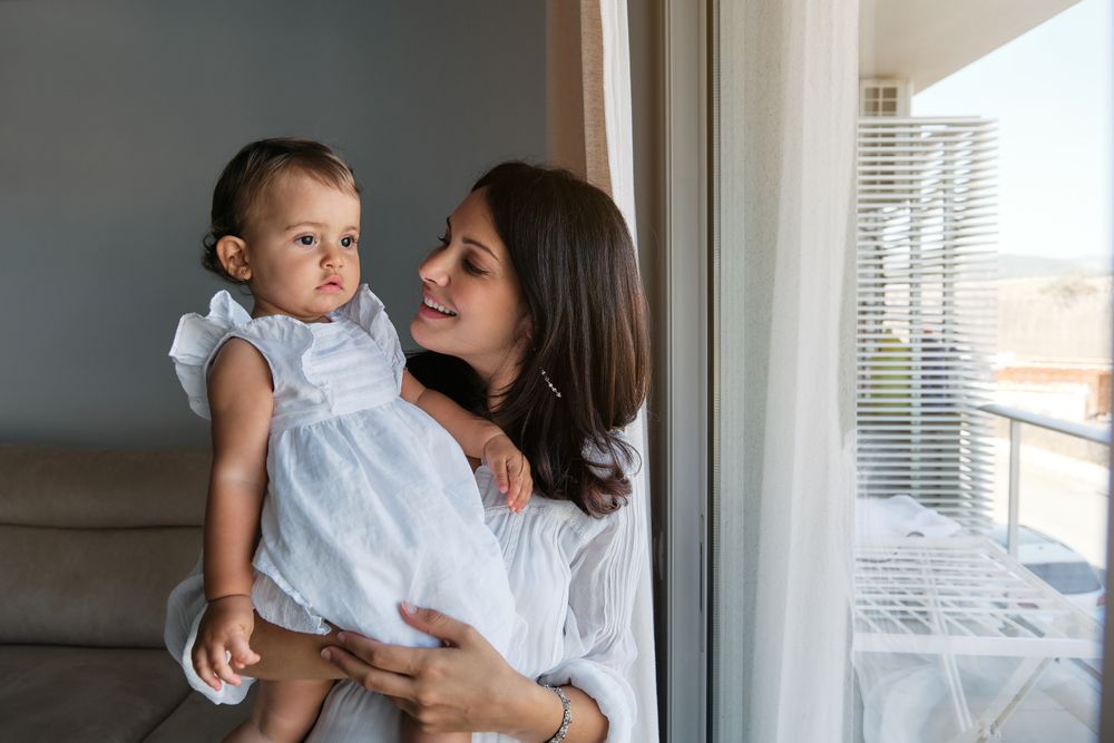 Loving mother looking at little daughter at home