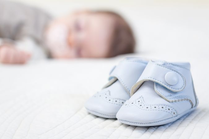 Baby blue shoes and babe sleeping on background