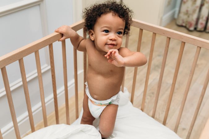 Cute baby boy in diaper in crib