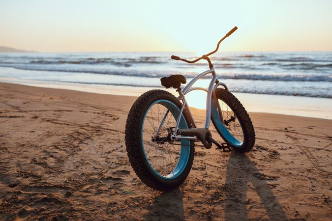 Modern fat bicycle parked at beach on sunset