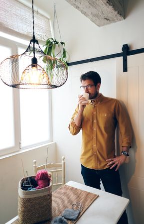 Man drinking hot tea during knitting