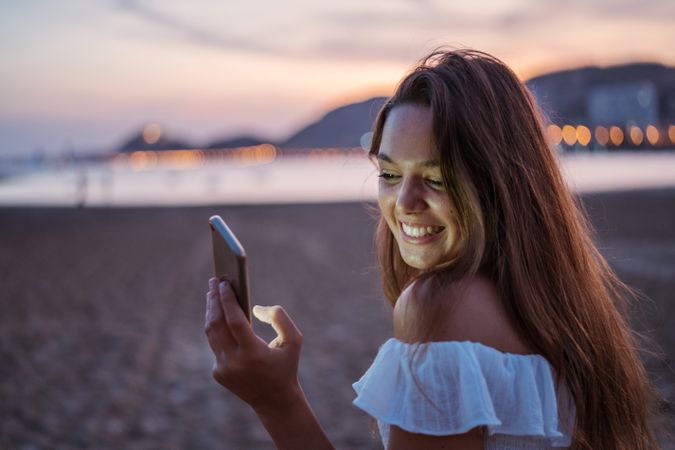 Cheerful young woman using smartphone on resort