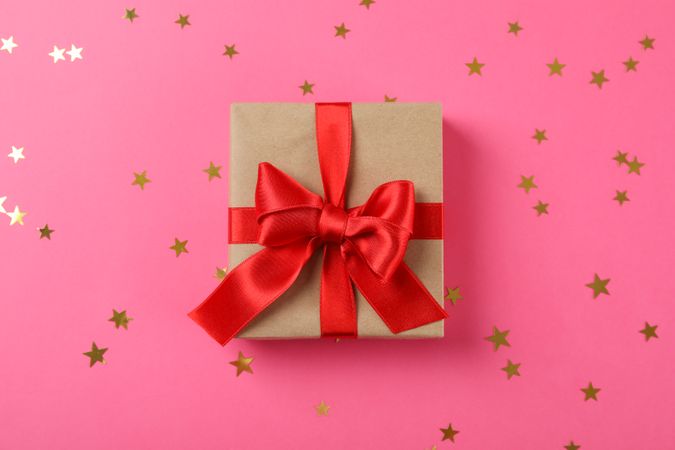Gift box with bow on decorated pink background, space for text