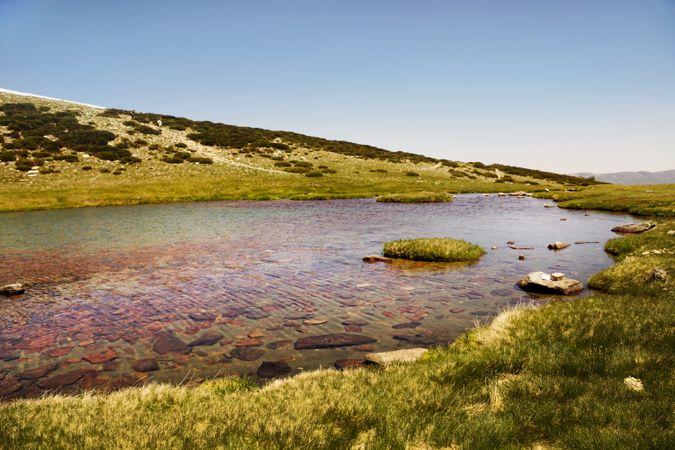 Clear lake at bottom of rocky mountain