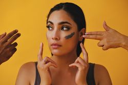 Latina woman with hands outreaching to apply mud mask