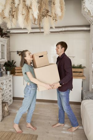 Young couple carrying big carton boxes in house