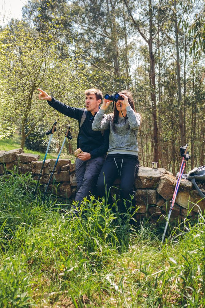 Couple doing trekking looking with binoculars