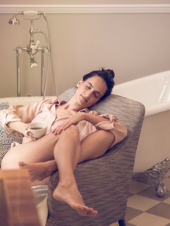 Relaxed woman resting on armchair with coffee