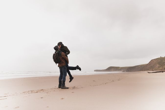 Couple kissing on sand shore near water