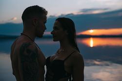 Couple hugging on beach of lake at sunset