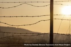 Sunrise behind a barbed-wire fence bx9Zn0