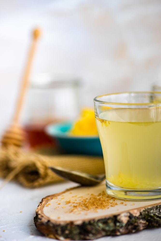 Side view of ginger detox drink on wooden tray