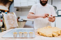Bearded confectioner putting dough into cup