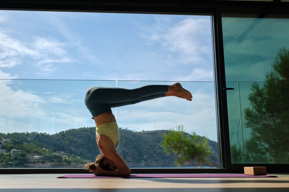 Slim woman practicing yoga in headstand on mat