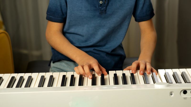 Close-up of child's hands pressing digital piano keys