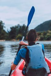Female kayaking with paddle in raised hands