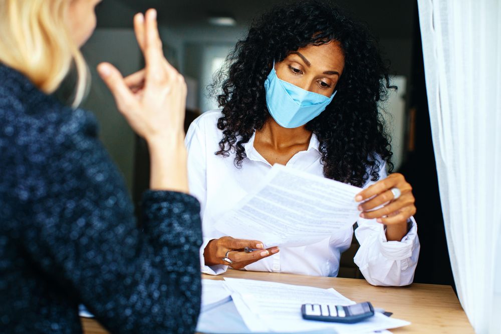 Woman with colleague looking surprised while reading documents