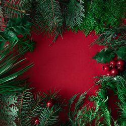 Festive leaves and branches bordering red background