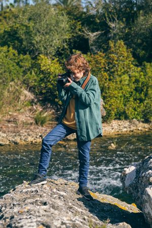 Focused boy taking photo on rocky coast