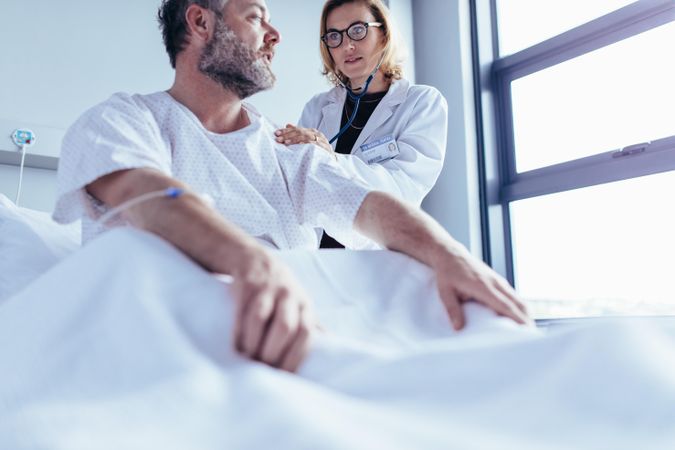 Male patient getting examined in hospital room by female physician