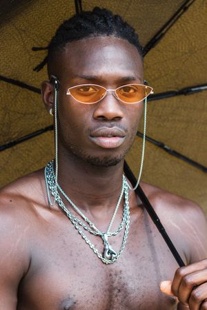 Stylish shirtless Black man with umbrella