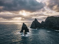 Sun peaking through the clouds along a rugged shoreline