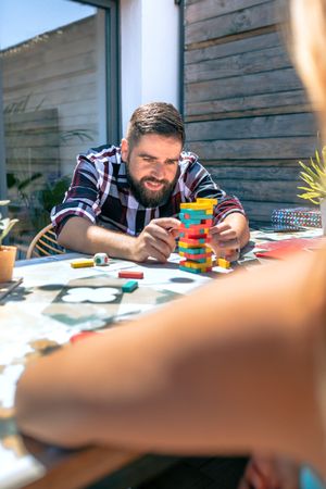 Bearded man catching game piece with colleague on terrace