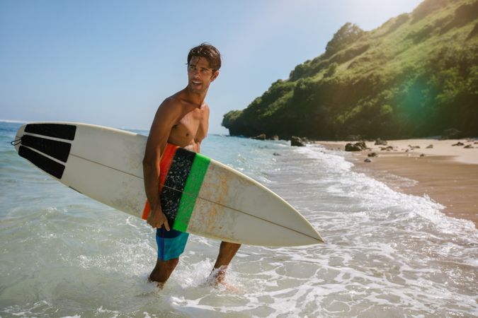 Handsome young man with surfboard on the beach