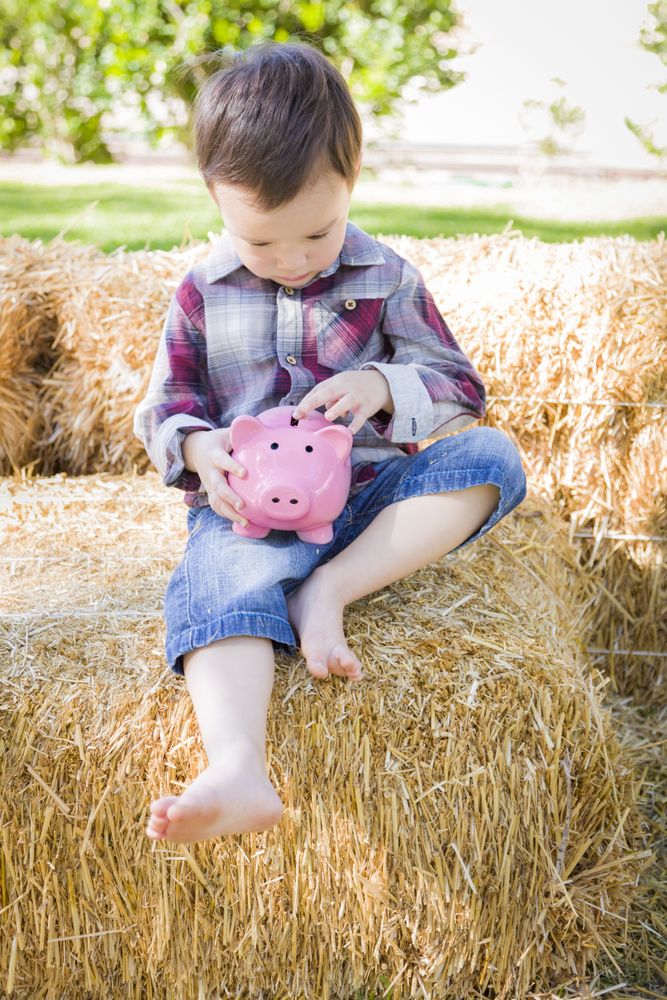 Cute Young Biracial Boy Putting Coins Into Piggy Bank