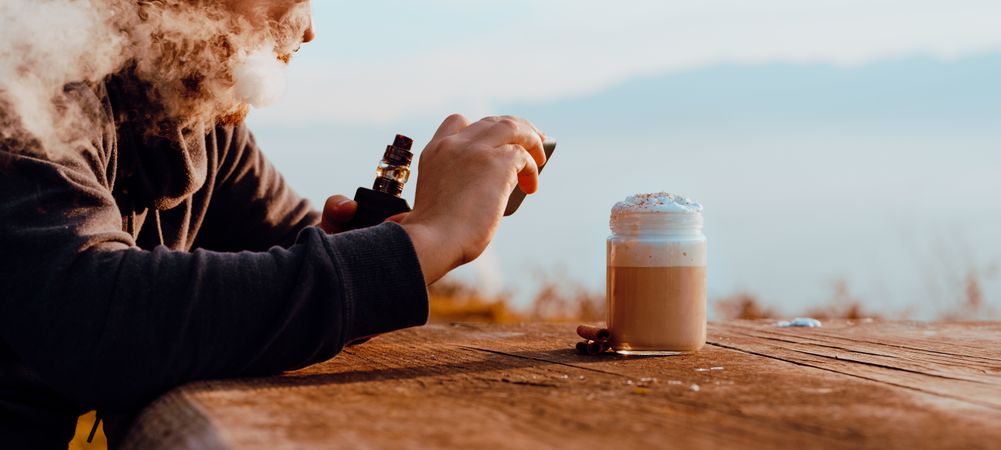 Vaper puffing smoke and taking shot of coffee