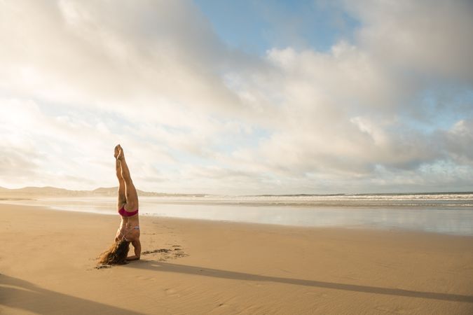 Woman doing handstand near sea