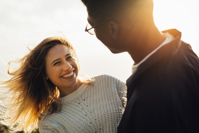 Smiling woman looking at her boyfriend against bright sun