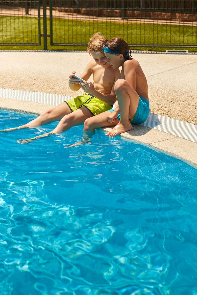 Boys on poolside taking selfie