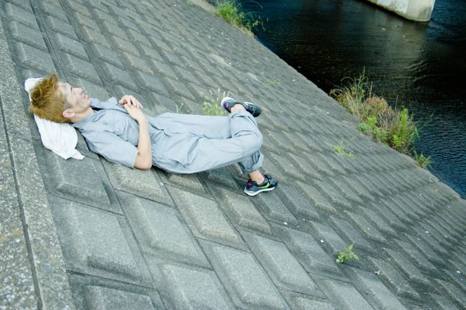Exhausted man in work suit laying on gray concrete pavement