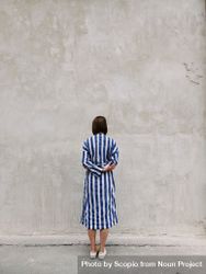 Backside of woman in blue and light dress standing in front of beige wall 41kaL0