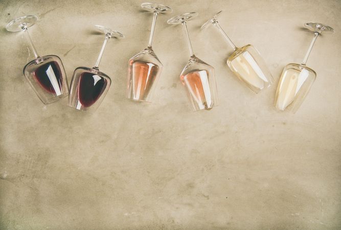 Glasses of wine laying on grey background, wide composition, copy space