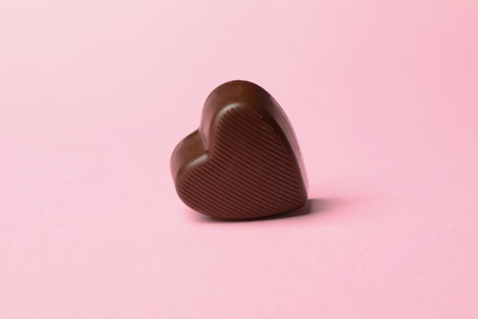 Chocolate candy in the heart form on pink background